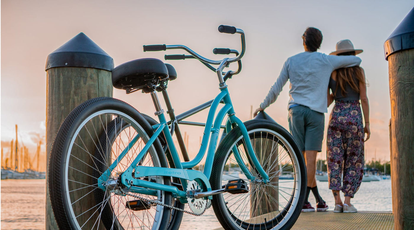 Couple standing on a boat dock viewing a sunset with their Sun Retro beach cruisers parked in the background